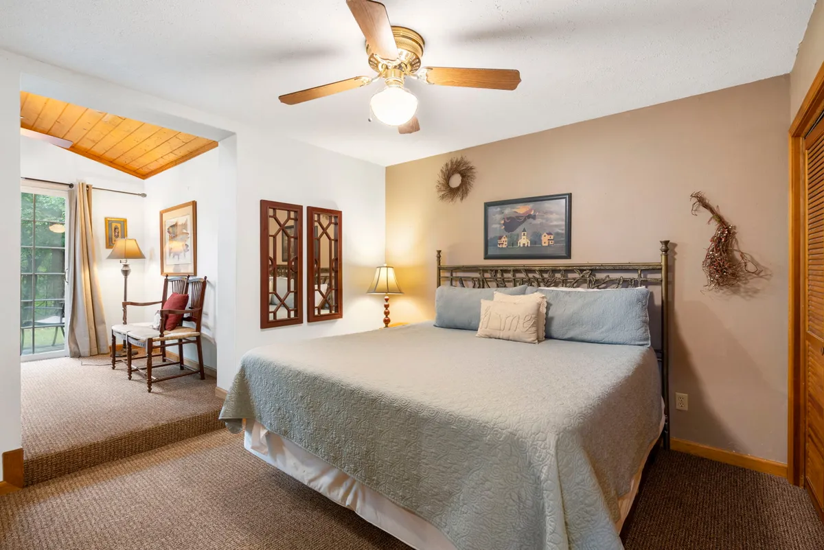 This image showcases a tranquil bedroom with a comfortable bed, decorative mirrors, a lamp, and artwork. The scene is bathed in soft, natural light, creating a calm and peaceful atmosphere perfect for rest and relaxation.