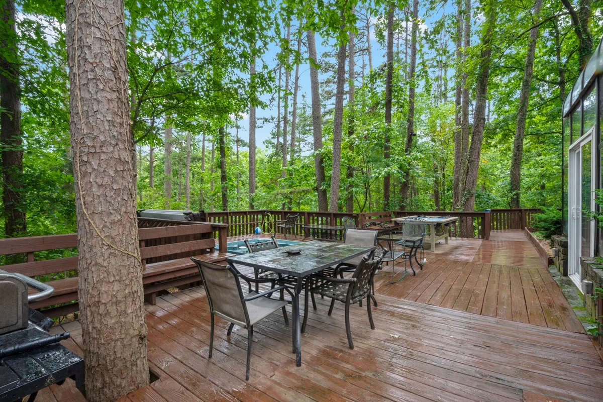A cozy section of a wooden deck with comfortable outdoor furniture, surrounded by trees. The setting is inviting and ideal for gatherings, enjoying morning coffee, or unwinding at sunset, with plenty of space for entertaining.